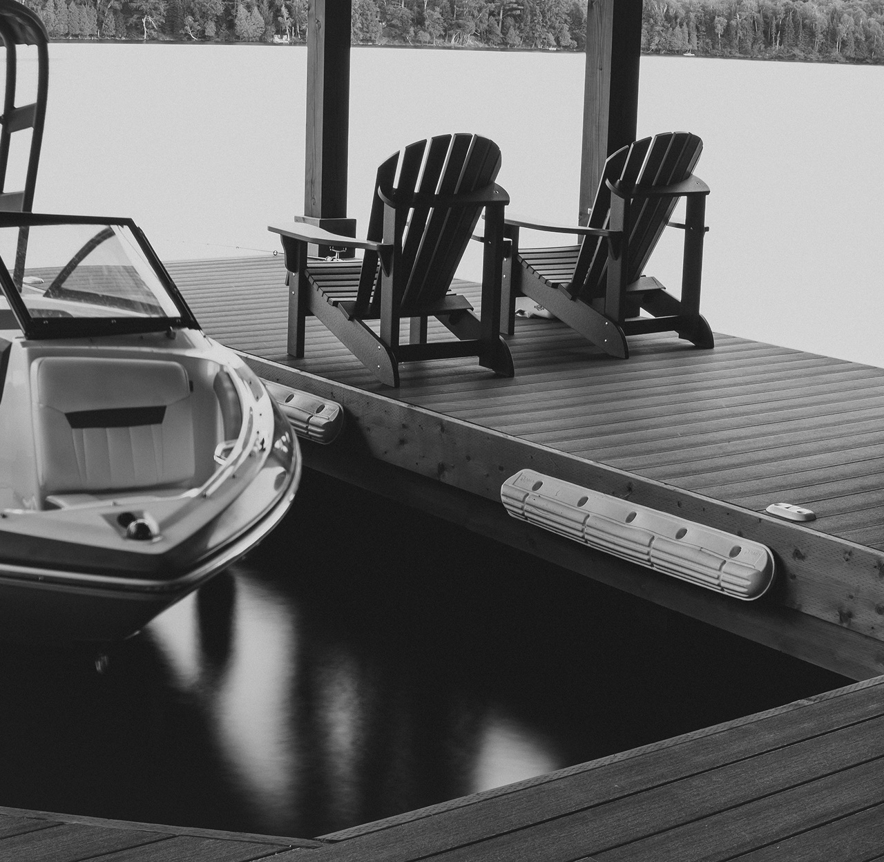 Muskoka chairs and a boat tied to a dock on an Ontario lake